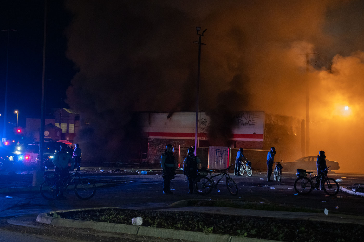 Buildings burn behind police officers in Minneapolis
