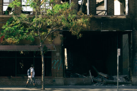 People walk by the burned out Foot Locker store on May 31, 2020 after it was burned in fires following the death of George Floyd.