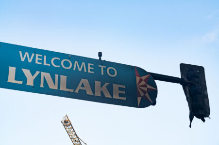 A burned "Welcome to Lynlake" sign on Lake Street and Lyndale Avenue on May 30, 2020. The sign was burned from dumpsters on fire below it after the murder of George Floyd.