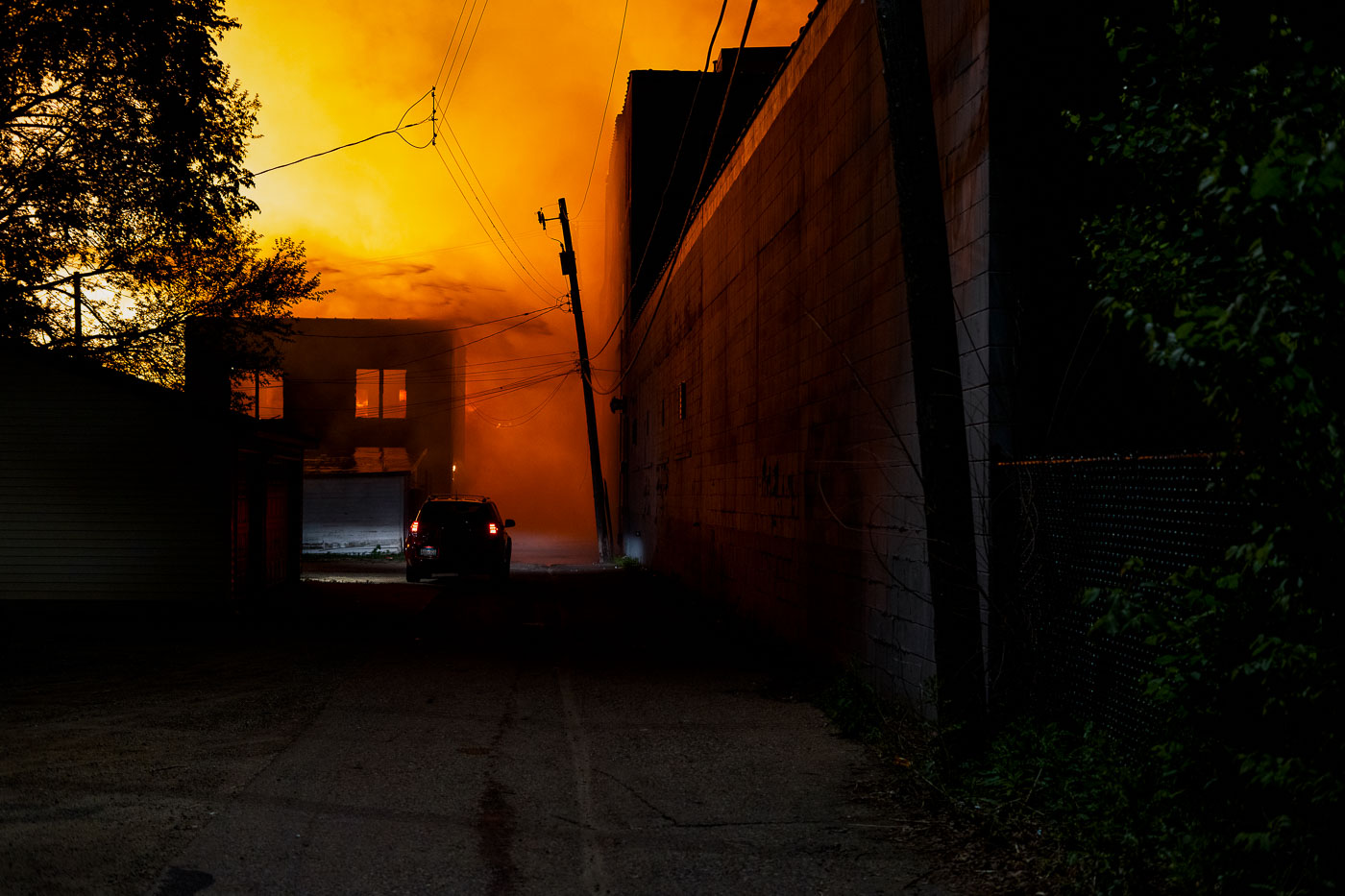 Car drives down an alley filled with smoke and fire during Minneapolis riots