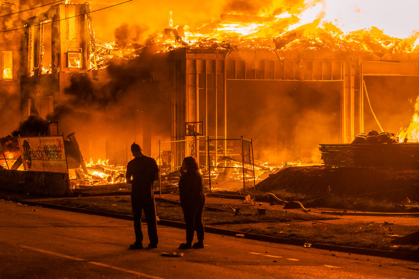 Couple stand in the road as a large building burns during George Floyd protests