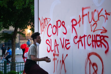 A man writes on a Target sign across from the Minneapolis police third precinct.