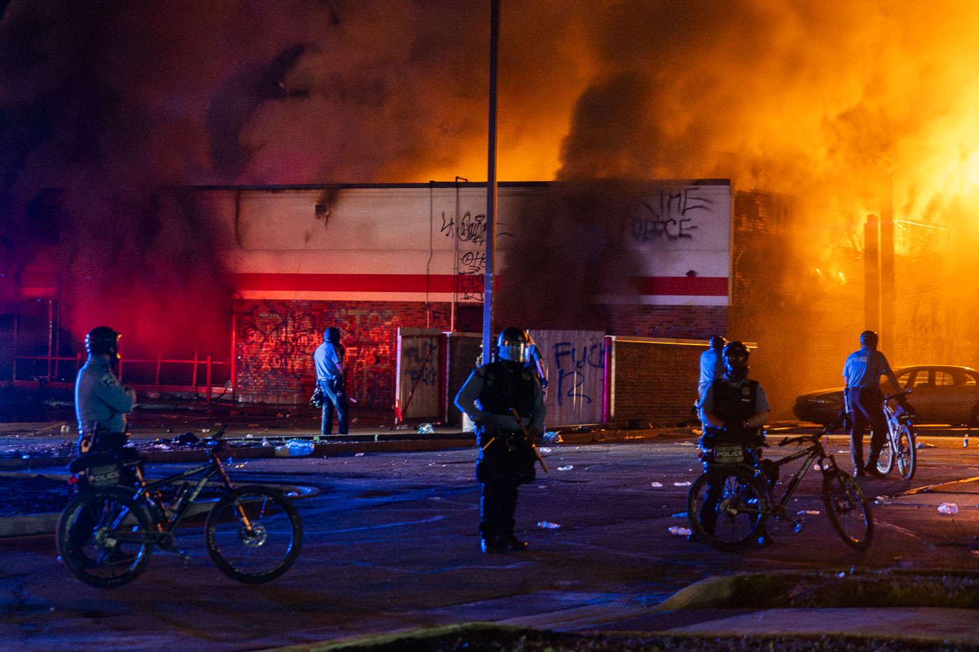 Police officers on bikes as buildings burn behind them