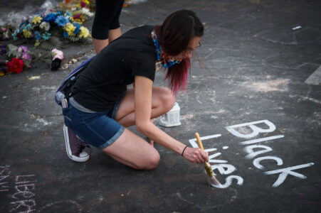 A woman paints Black Lives Matter at the George Floyd memorial at 38th St and Chicago Ave on May 31, 2020.
