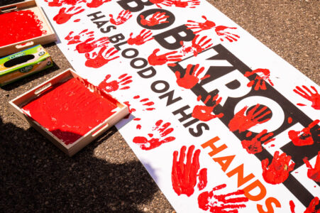 Protesters dip their hands in red paint to leave hand prints on a protest banner that reads “Bob Kroll has blood on his hands”. The protest outside of the Minneapolis police union headquarters where Bob Kroll was the union head for many years.