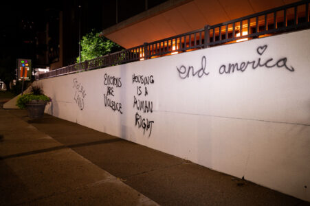 Stolen Land, Housing is a human right, end America written on the side of the Hennepin County Medical Center.