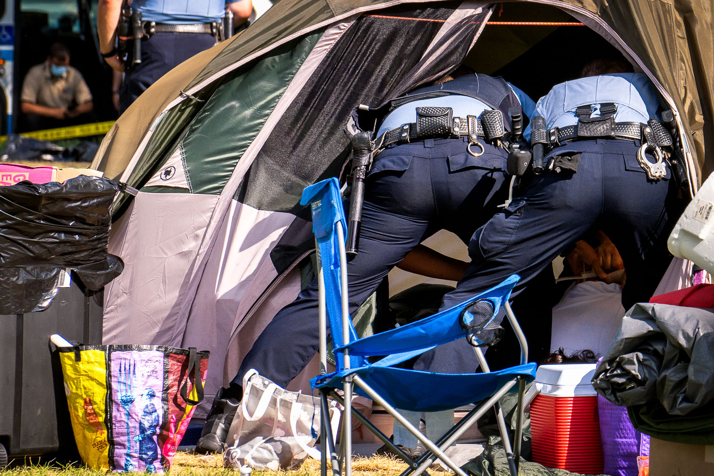 Police officers handcuffing people living in tents in Minneapolis