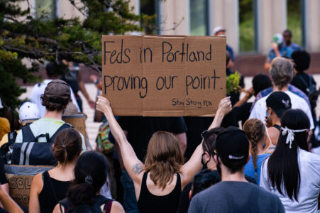 A woman holds up a sign that reads “Feds in Portland proving our point. Stay Strong PDX” outside the Federal Courthouse in downtown Minneapolis. Protesters gathered on July 23rd, 2020 to protest federal officers being deployed to cities around the country.
