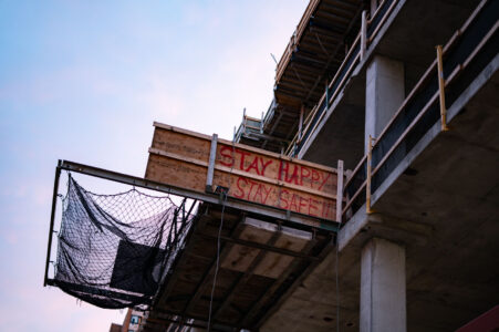 Construction site in downtown Minneapolis with wood that reads “Stay happy stay safe”.