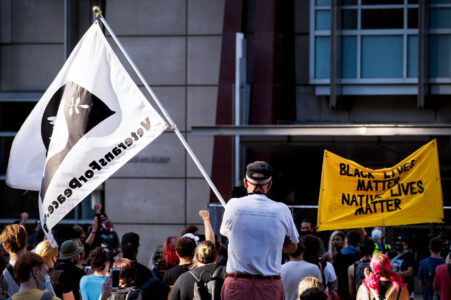 A veteran holds up a Veterans For Peace flag at a protest outside the Federal Courthouse in downtown Minneapolis. Protesters gathered on July 23rd, 2020 to protest federal officers being deployed to cities around the country.