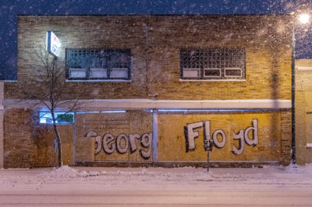 Storefront boards reading "George Floyd" on Lake Street during snowfall.