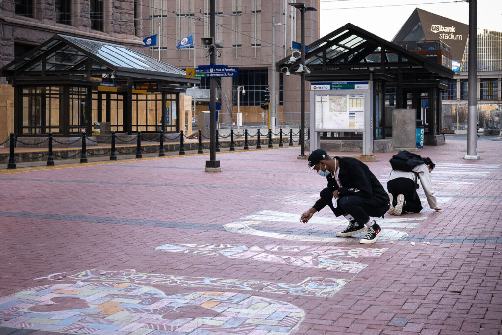 A couple walked by and picked up chalk to help finish a Black Lives Matter mural during the Derek Chauvin murder trial.