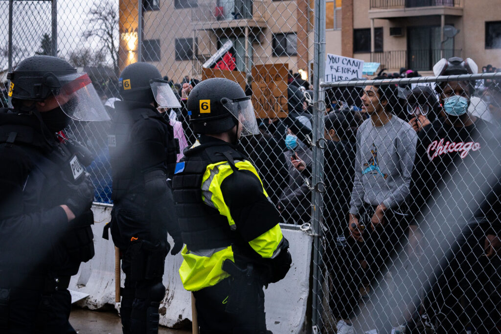 Protesters and police officers with fencing in between them.