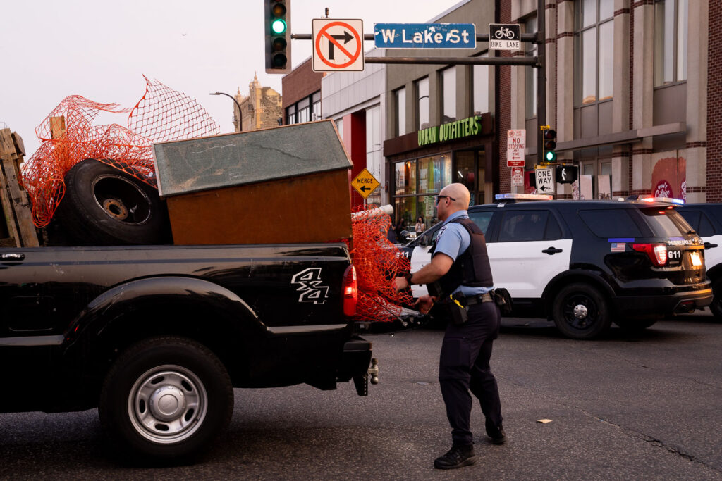Minneapolis police load up a pickup with materials being used by protesters for barricades.