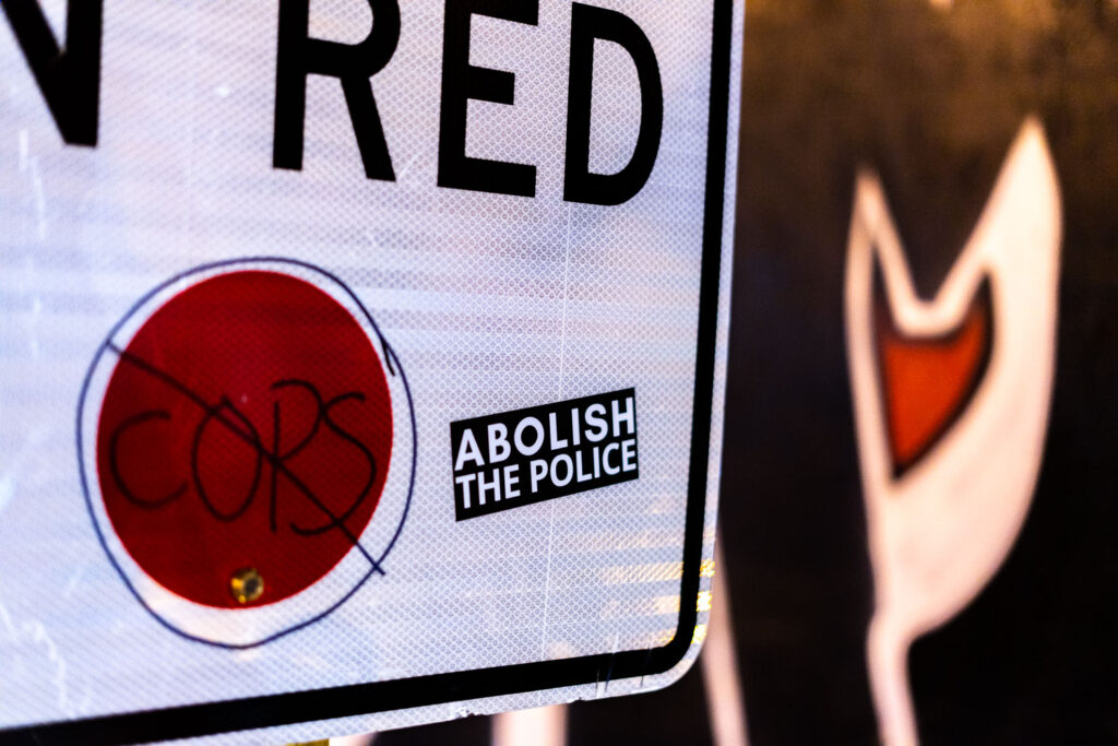 An Abolish The Police sticker on a No Turn on Red sign in Uptown Minneapolis.