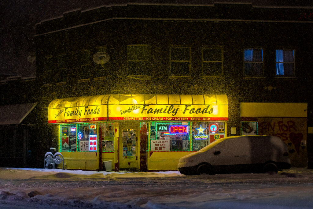 Longfellow Family Foods corner store on Minnehaha Ave in Minneapolis during a December snowfall.
