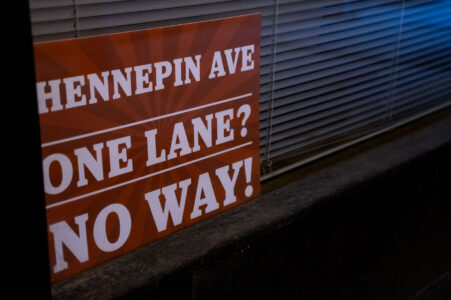 A sign in a window reading "Hennepin Ave. One Lane? No Way!"
