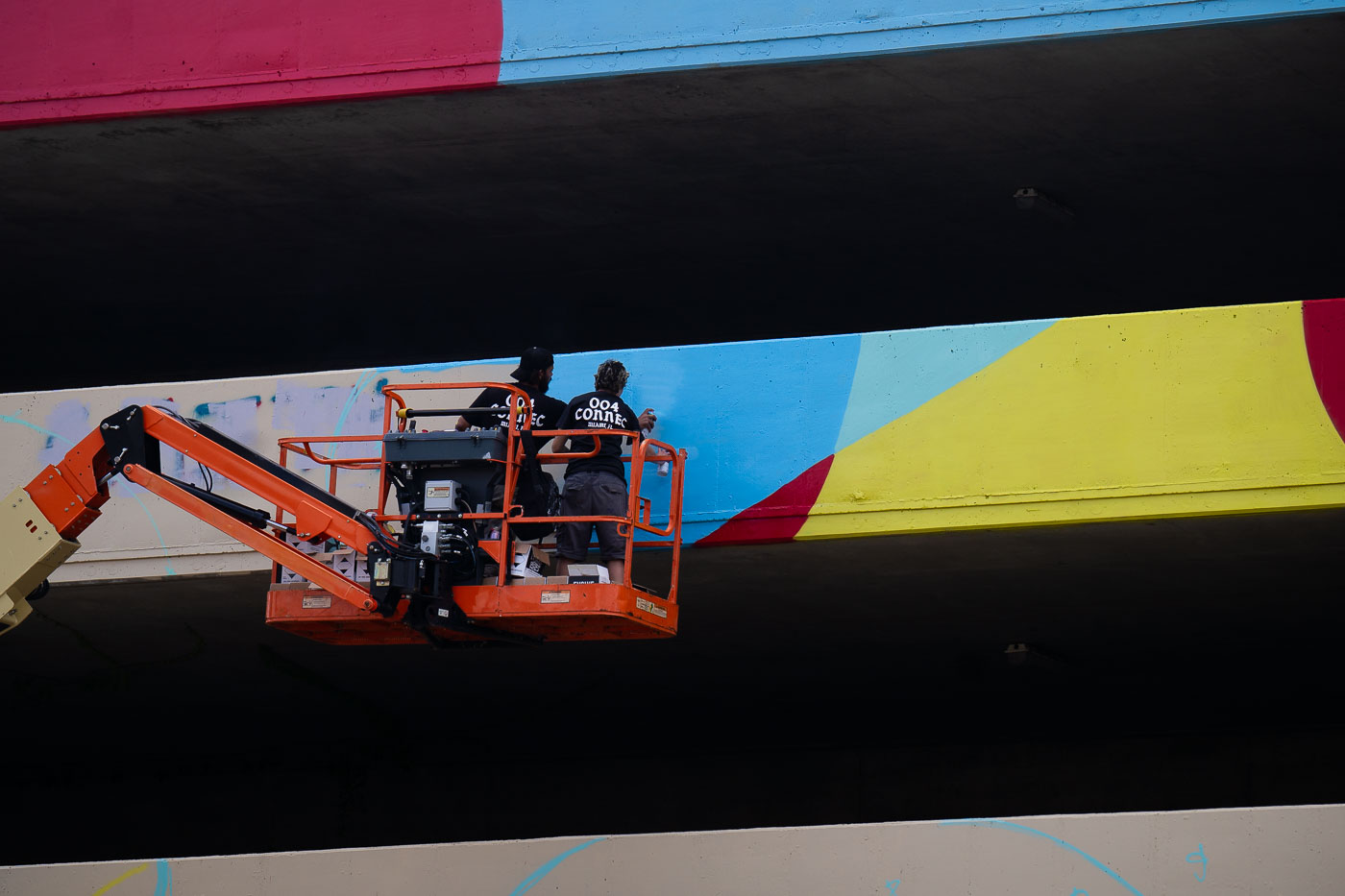 Artists paint a mural on parking garage