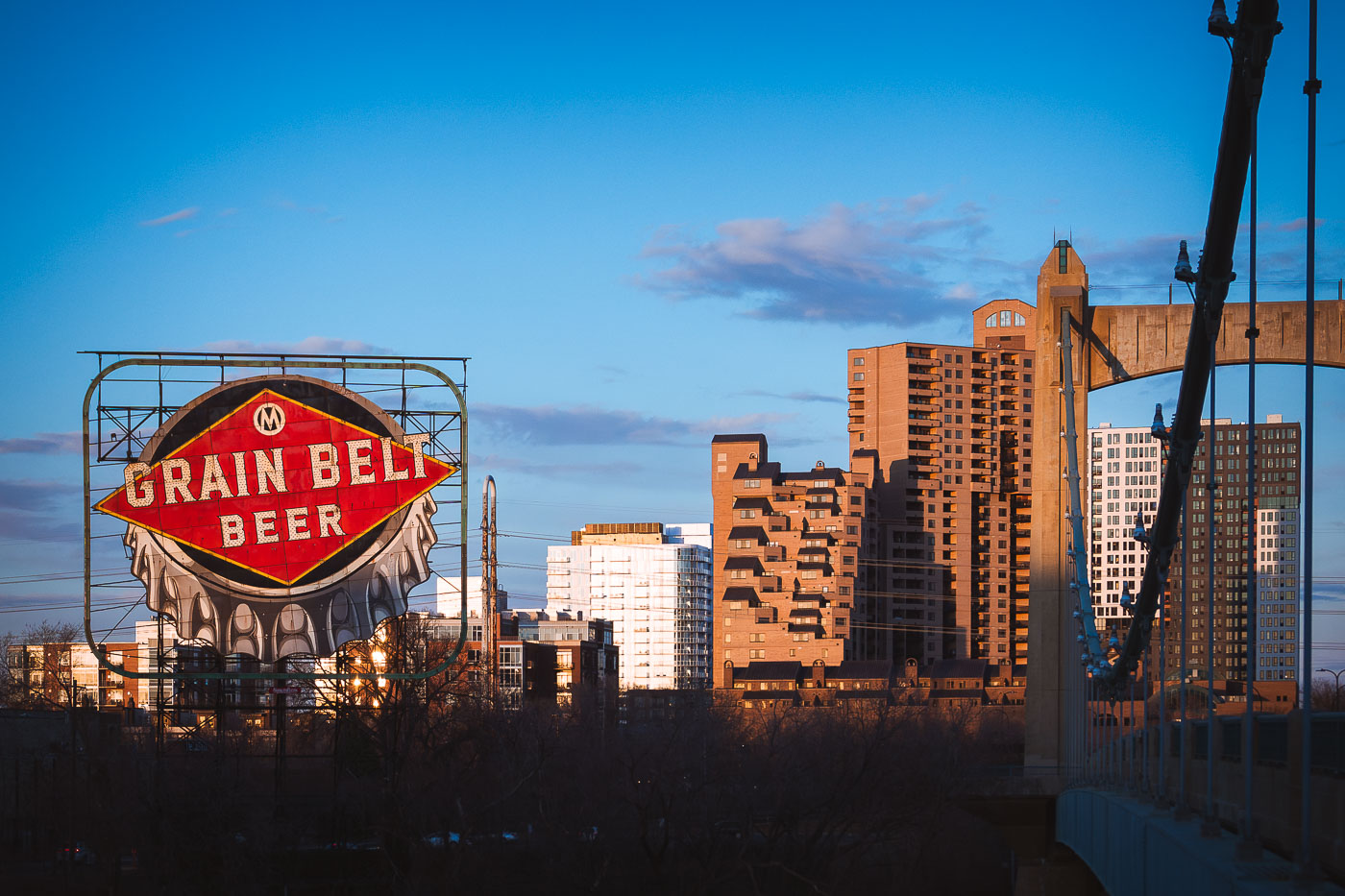 A Grain Belt Beer sign on the shores of the Mississippi River and the Hennepin Avenue Bridge. March 2024.