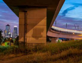 A light rail train over the bridge with downtown in the background.
