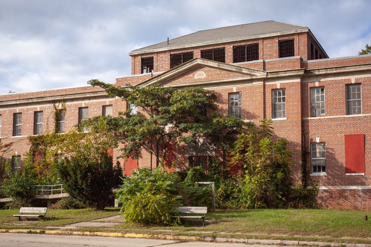 Brick institutional building with barred windows and overgrown vegetation at Kings Park Psychiatric Center, New York.