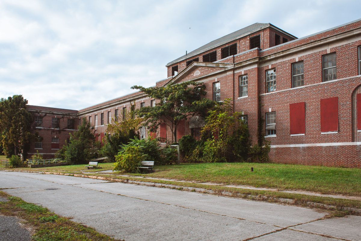 Brick institutional buildings with boarded windows and overgrown courtyard at Kings Park Psychiatric Center, New York.