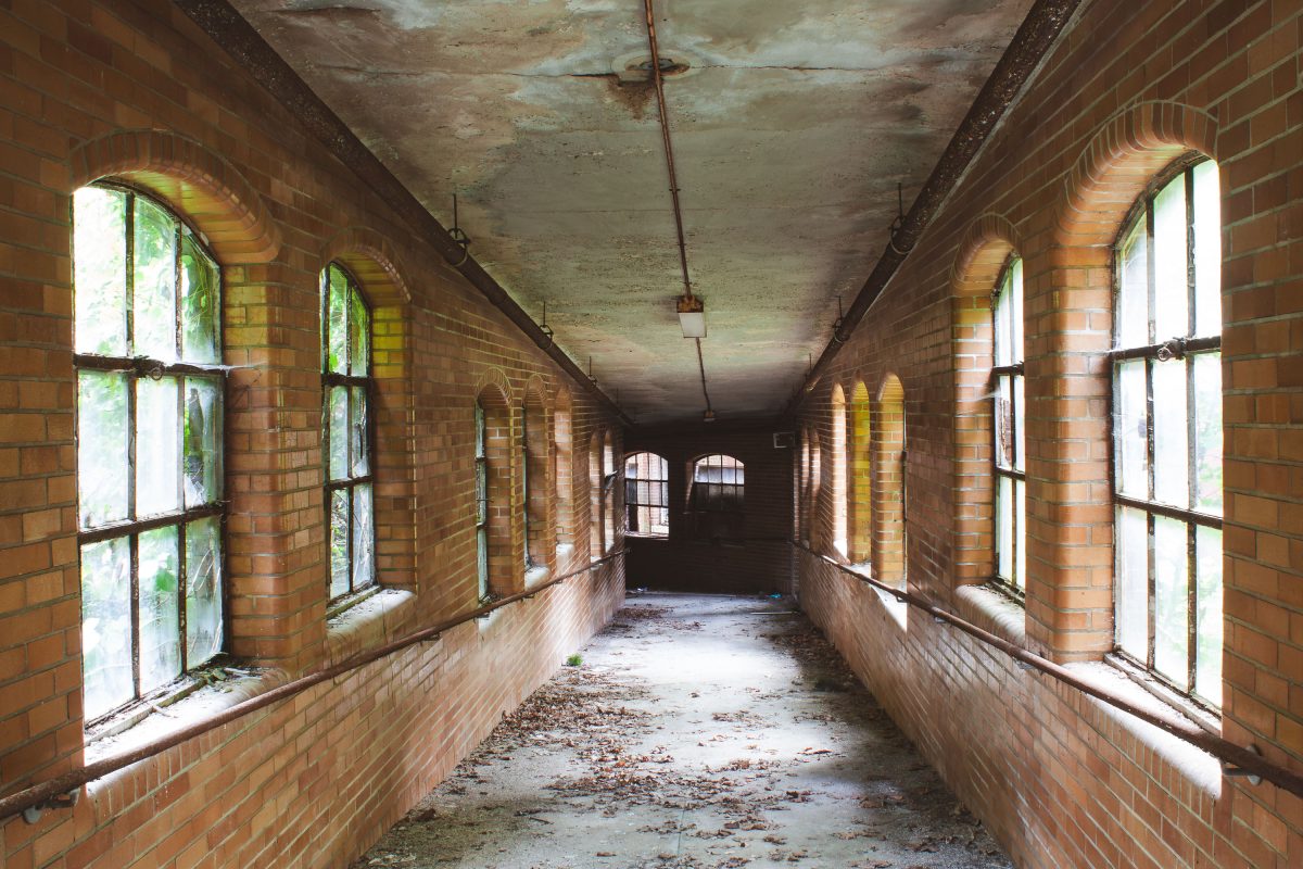 Deteriorated brick corridor with barred windows in abandoned Kings Park Psychiatric Center, New York.