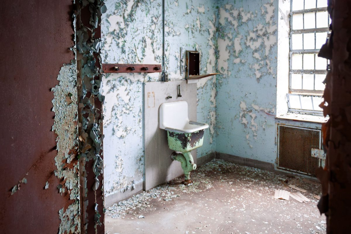 Deteriorating bathroom with peeling paint and green mold in abandoned Kings Park Psychiatric Center, New York.