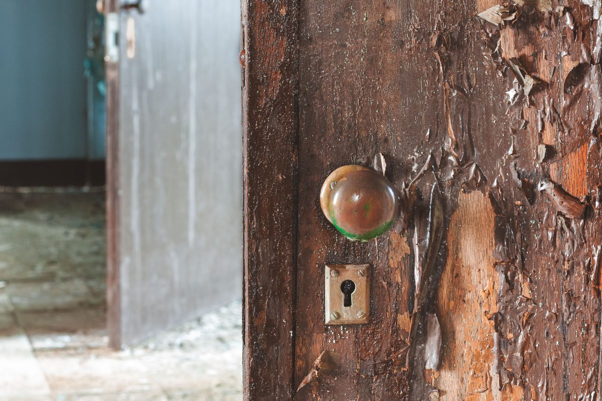 Weathered wooden door with tarnished brass knob and keyhole at Kings Park Psychiatric Center.