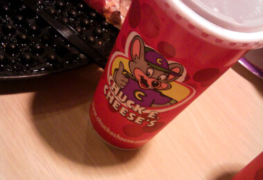 A slice of pizza and a bright red cup capture the familiar chaos of a Chuck E. Cheese table—half party, half nostalgia. The scene feels frozen in time: greasy trays, cartoon mascots, and the unmistakable buzz of arcade noise just beyond the frame. It’s an image of American childhood that hasn’t changed much in decades.