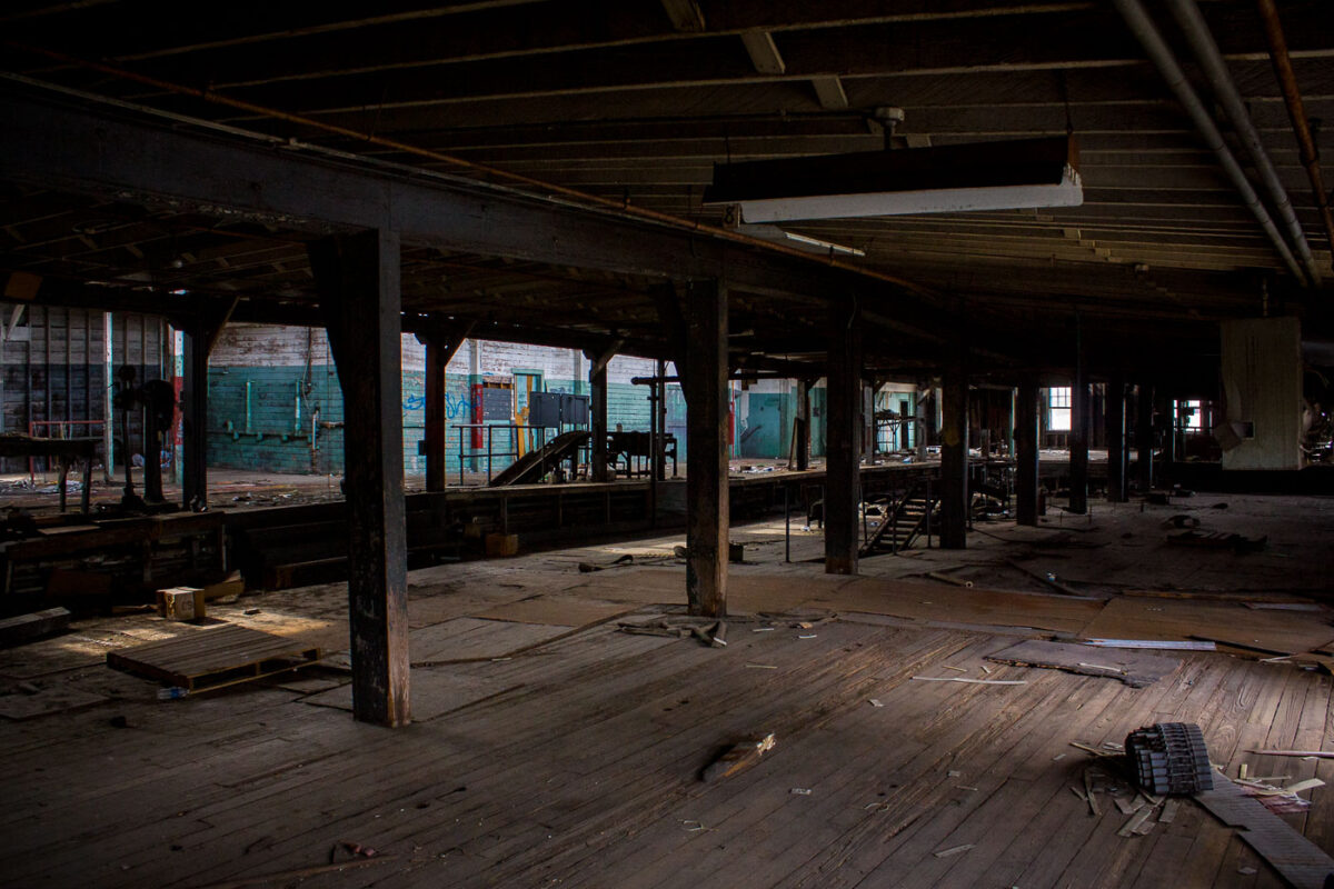 Interior of the abandoned Dixie Brewery in New Orleans, showing decaying wooden floors, exposed beams, and graffiti. The brewery ceased operations in the early 2000s.