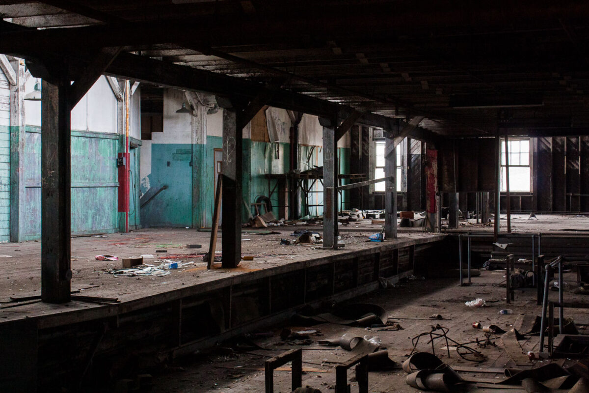 Interior of the abandoned Dixie Brewery in New Orleans, showing a large, open space with debris and natural light illuminating the disused industrial setting.