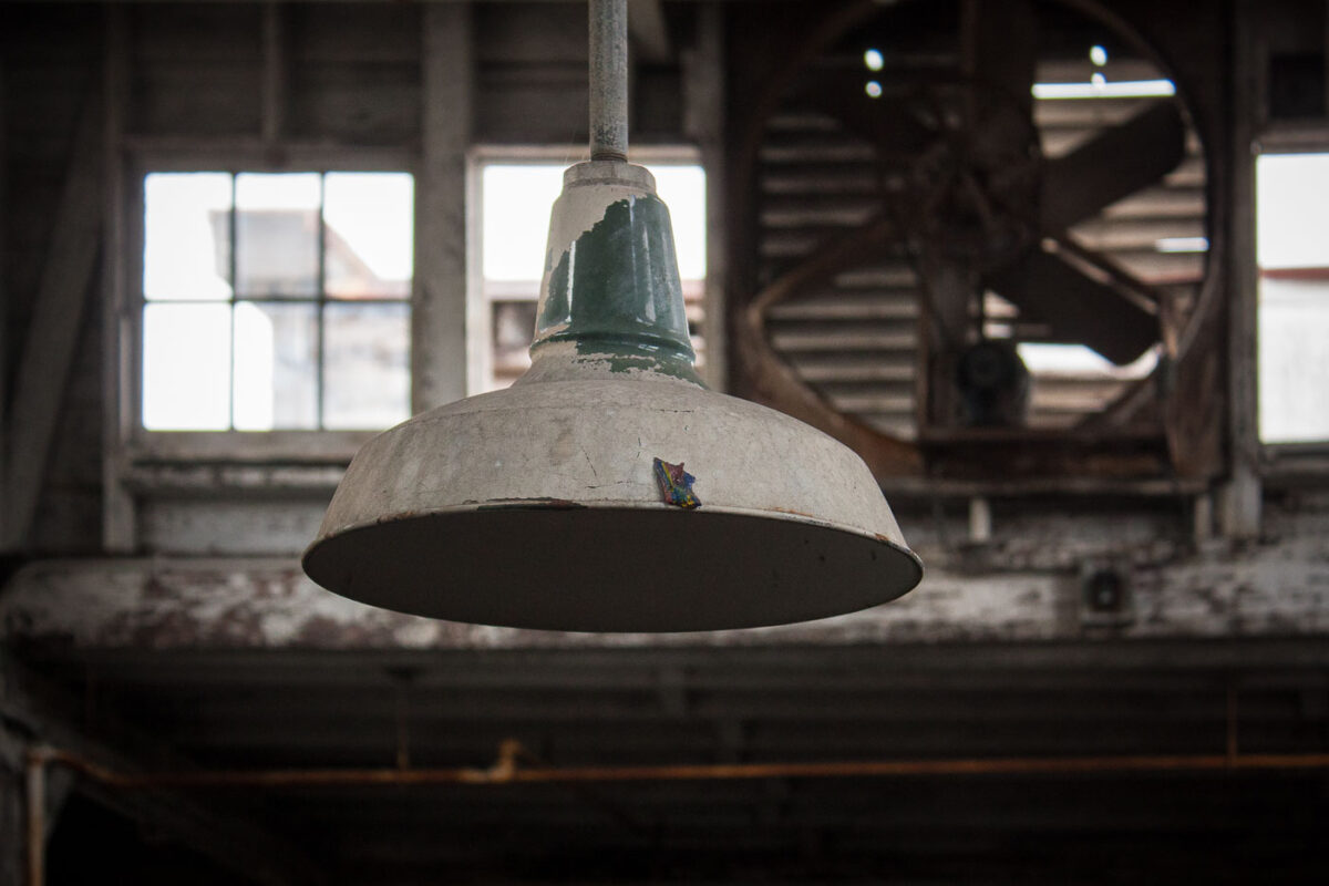 A weathered industrial light fixture hangs in the abandoned Dixie Brewery in New Orleans, a landmark that ceased operations after Hurricane Katrina.
