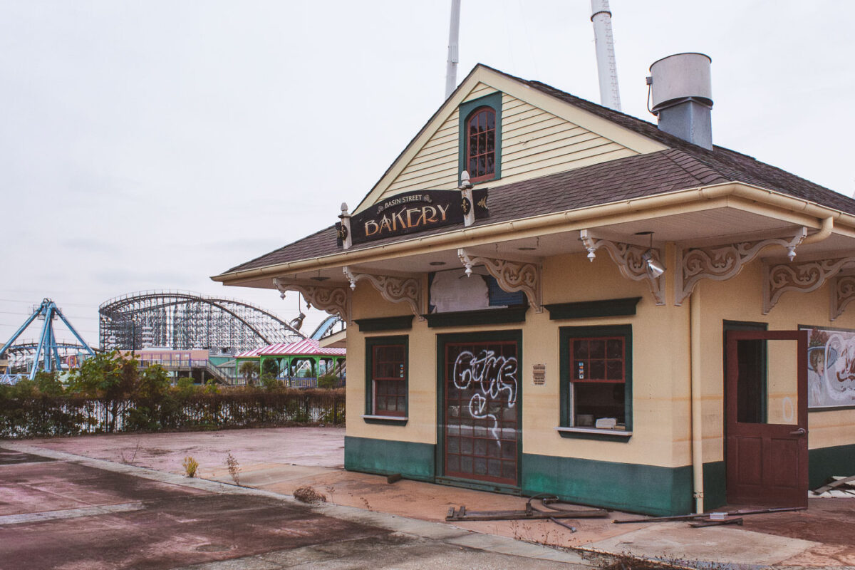 The abandoned Basin Street Bakery at Six Flags New Orleans, damaged by Hurricane Katrina, with roller coasters visible in the background.