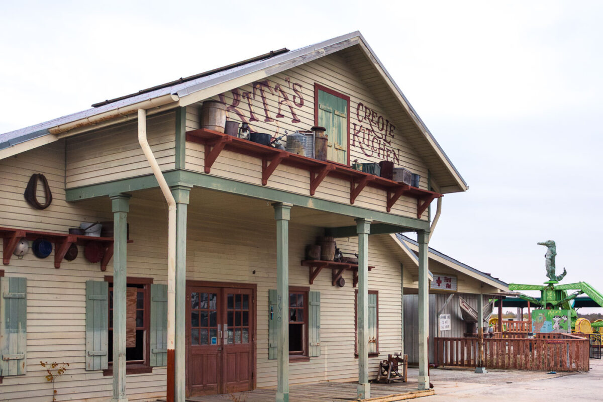 The abandoned Creole Kitchen building at Six Flags New Orleans, damaged by Hurricane Katrina, displays weathered signage and rustic shelving.