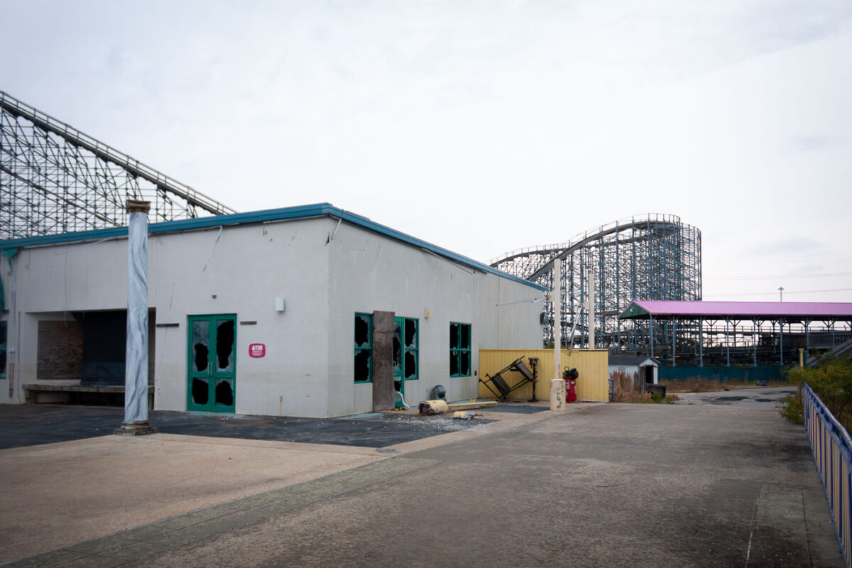 Six Flags New Orleans amusement park, damaged by Hurricane Katrina, with a roller coaster structure visible over a building with broken windows.