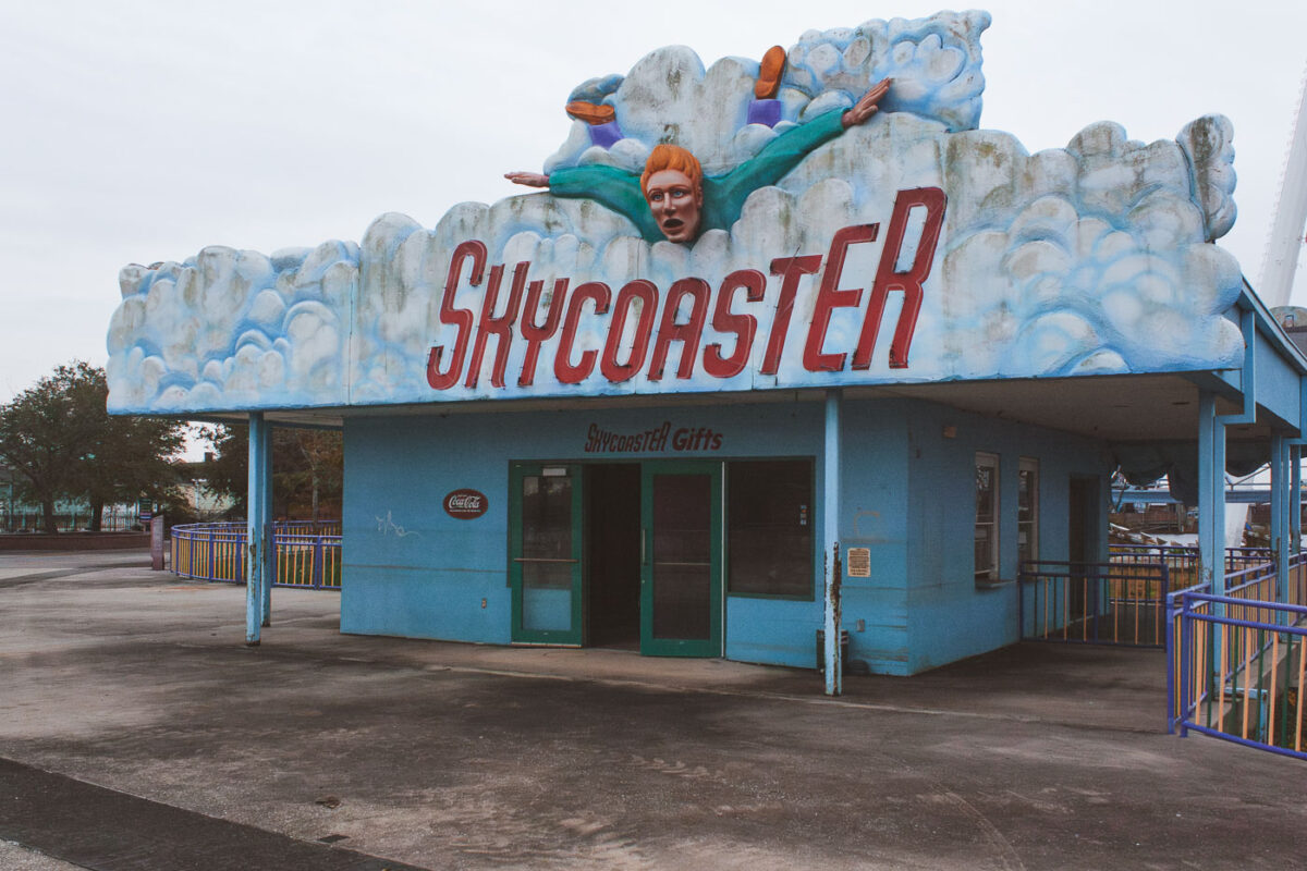The Skycoaster Gifts building at Six Flags New Orleans, abandoned after Hurricane Katrina, features a cloud facade and a figure in mid-air.