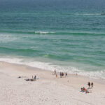 Beach goers walking in Panama City Beach 4 People lay and walk on the beach in Panama City Beach, Florida.