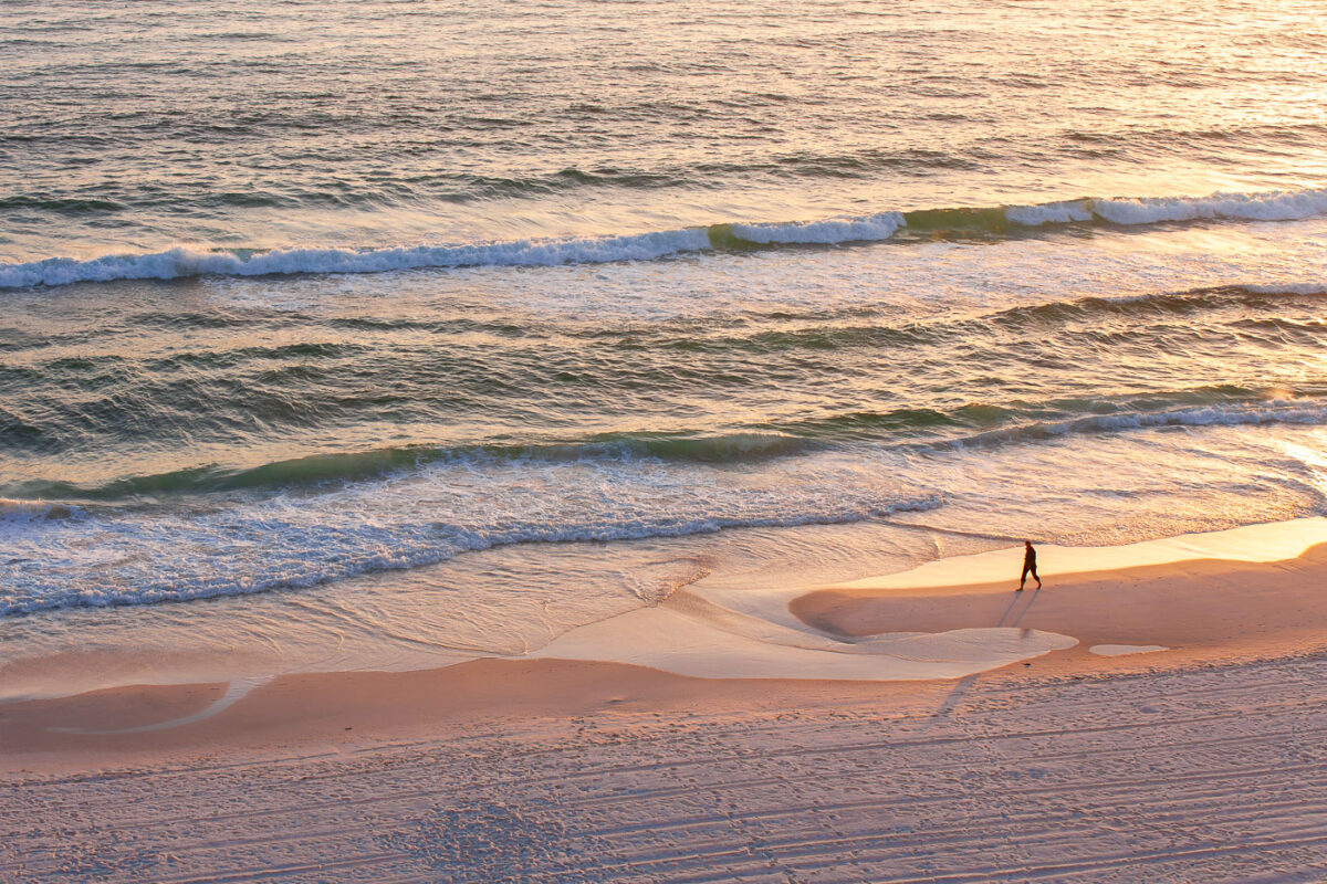 Person walks on the beach of the Gulf of Mexico in Panama City Beach, Florida.