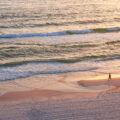 Person walks on the beach of the Gulf of Mexico in Panama City Beach, Florida.