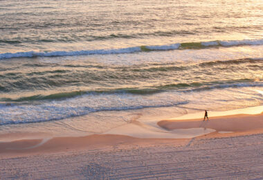 Person walks on the beach of the Gulf of Mexico in Panama City Beach, Florida.