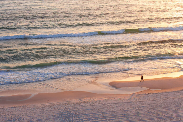 Person walks on a Gulf of Mexico beach 2 Person walks on the beach of the Gulf of Mexico in Panama City Beach, Florida.