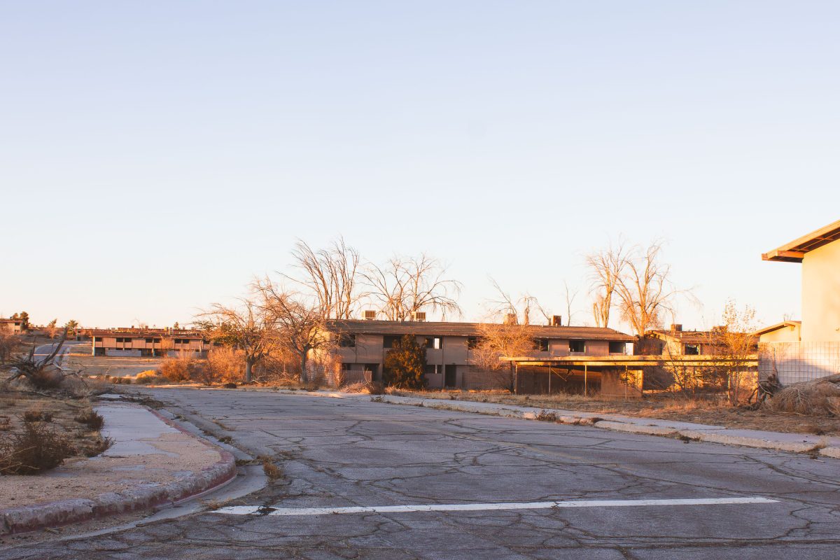 Abandoned residential buildings with bare trees along cracked pavement at George Air Force Base in Victorville, California.