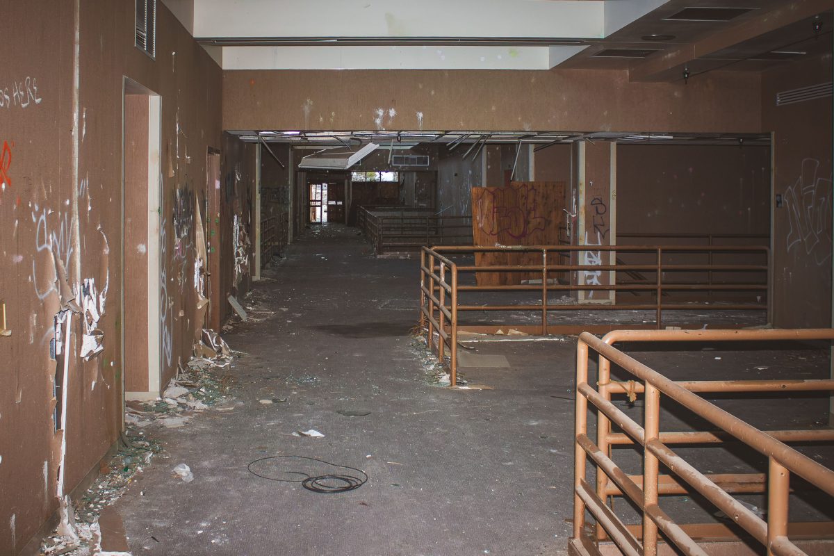 Abandoned interior corridor with rusted metal railings and graffiti-covered walls at George Air Force Base.