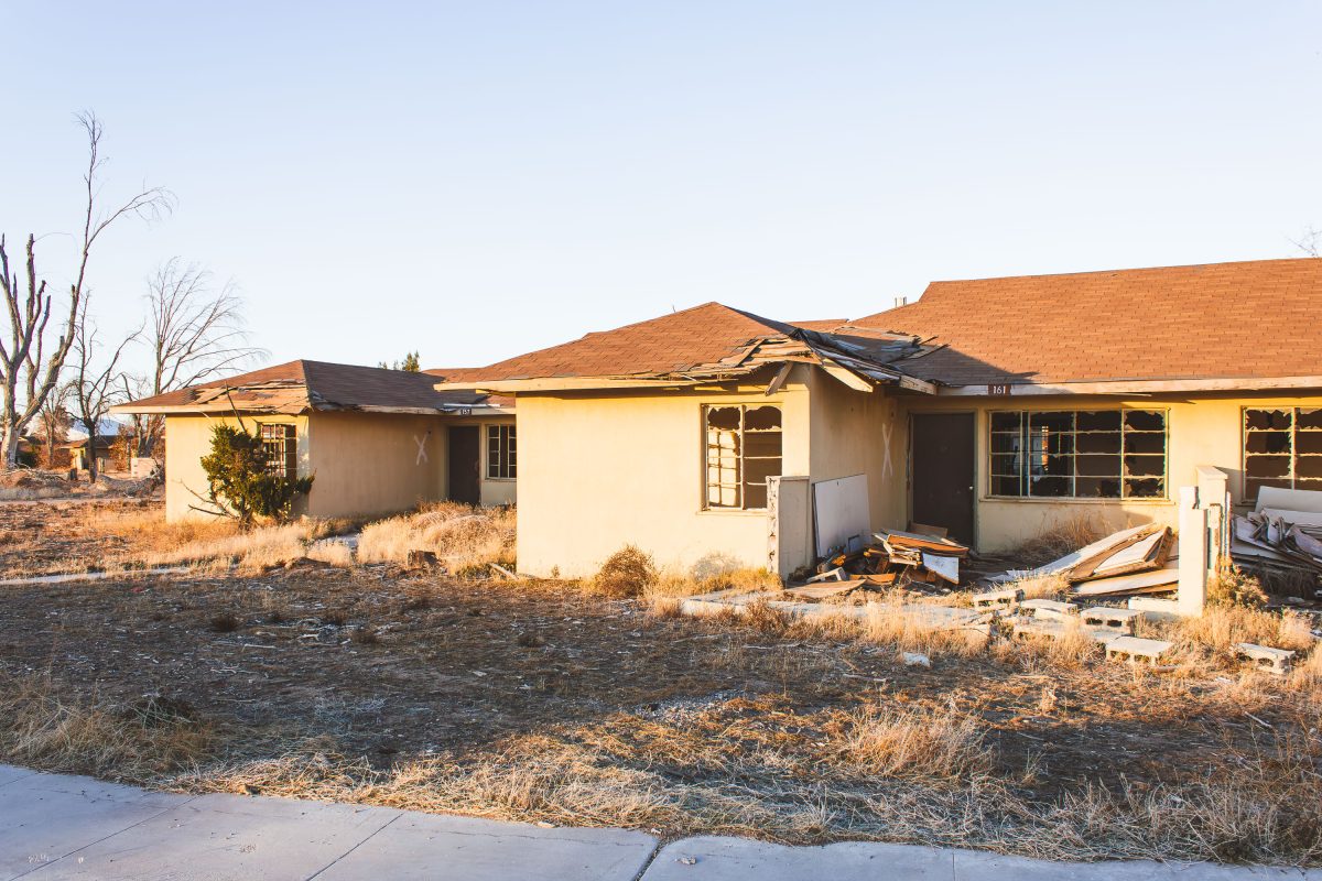 Abandoned residential building with damaged roof and broken windows at George Air Force Base in Victorville.