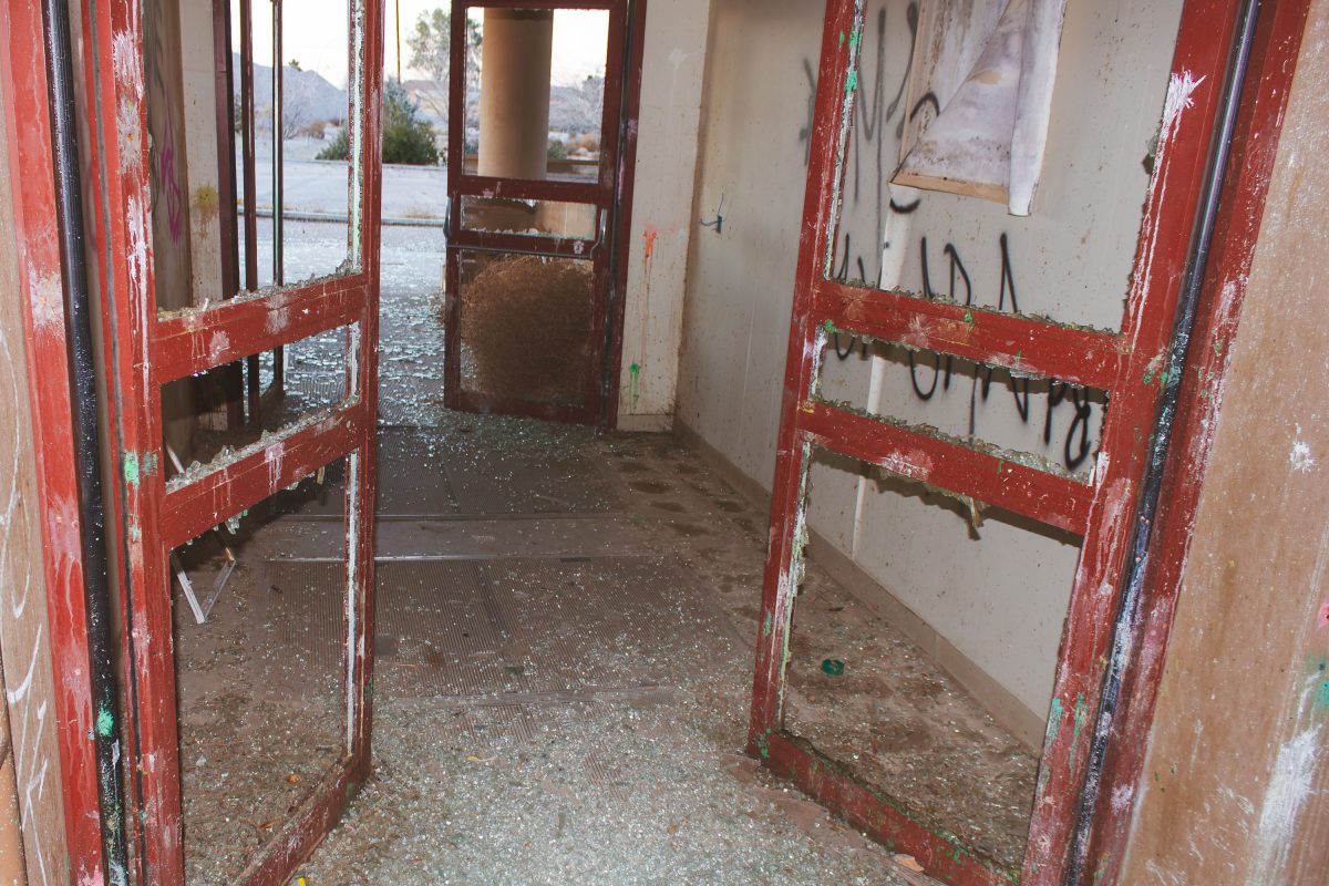 Deteriorated interior hallway with red doors and graffiti-covered walls at abandoned George Air Force Base.