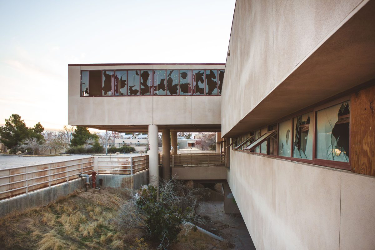 Modernist concrete building with silhouetted figures in upper window at abandoned George Air Force Base in Victorville.