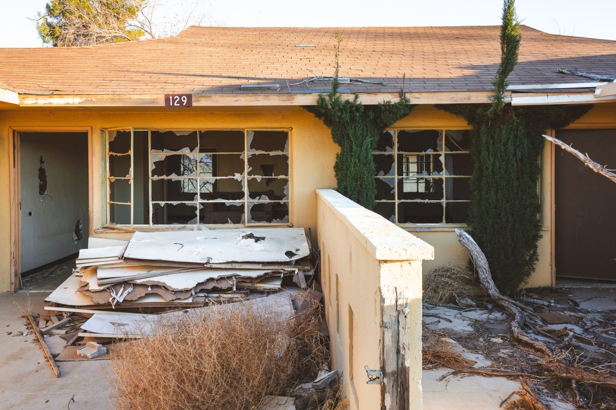 Abandoned residential building numbered 129 at George Air Force Base in Victorville, California, with broken windows and debris.