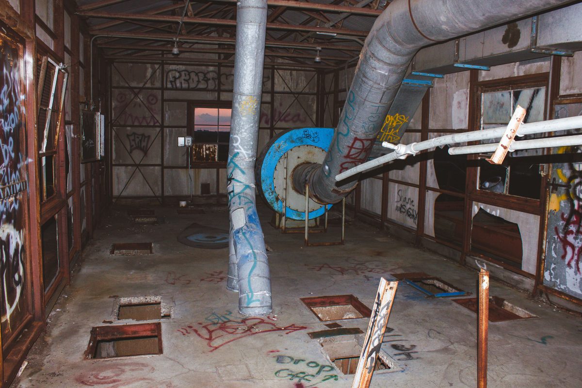 Abandoned Fruen Mill interior in Minneapolis with graffiti-covered support column, rusted industrial pipes, and deteriorating
