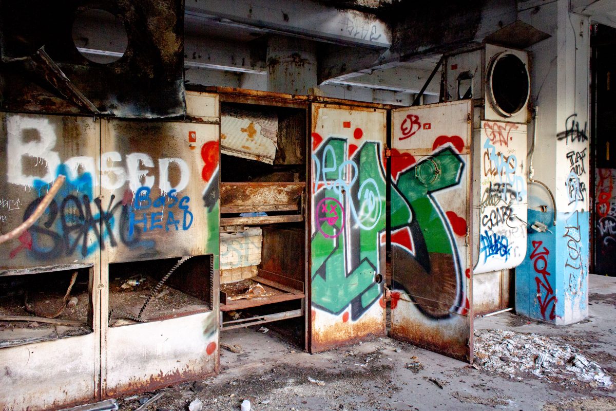 Rusted industrial machinery and graffiti-covered metal doors inside the abandoned Fruen Mill grain processing facility in